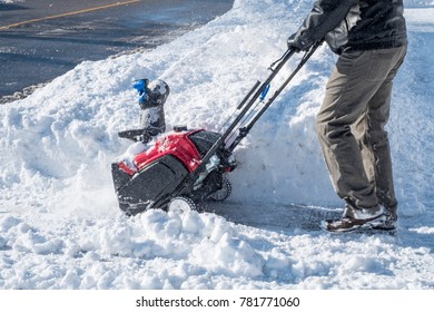 Man Removing Snow With A Snowblower in a Suburb Neighborhood on a Sunny Day - Powered by Shutterstock