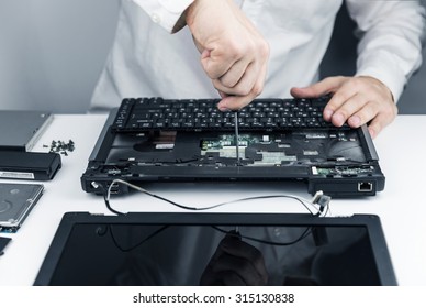 man repair laptop motherboard with screwdriver white coat 