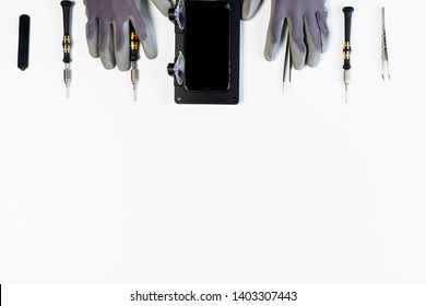 Man Repair Mobile Phone Broken Display Copy Space Top Flat Lay. Hands In Glove Dismantle Smartphone Crack Glass On White Background. Cellphone Holder Tool Overhead. Telephone Screwdriver Fix Isolated