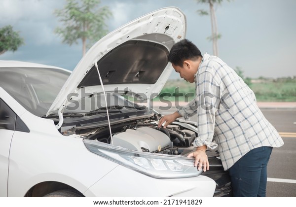 Man repairing a broken car by the road. Man
having trouble with his broken car on the highway roadside. Man
looking under the car hood. Car breaks down on the autobahn.
Roadside assistance
concept.