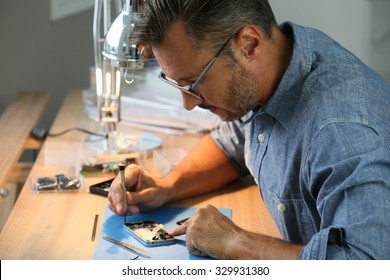 Man repairing broken smartphone in workshop