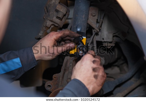 The man is repairing the disc brake in the car.\
Repair disc brake.