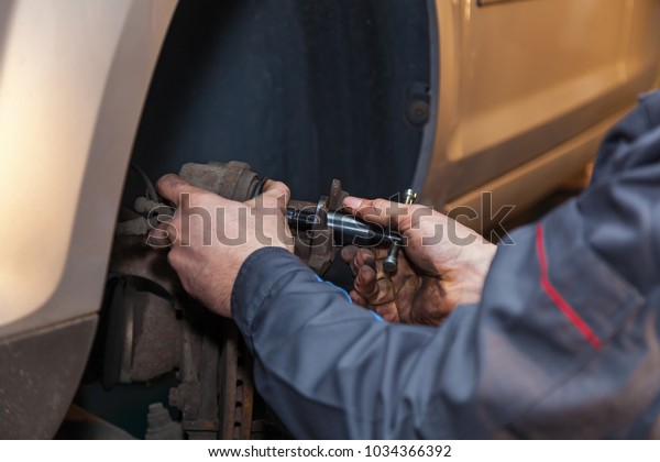 The man is repairing the disc brake\
machine, close-up. Disk brake repair in the\
car.