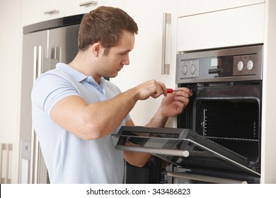 Man Repairing Domestic Oven In Kitchen