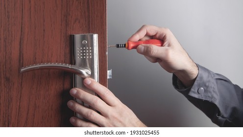 Man repairing door lock. Hand of the repairman with a screwdriver