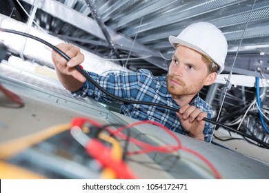 Man Repairing Electrical Wiring On The Ceiling