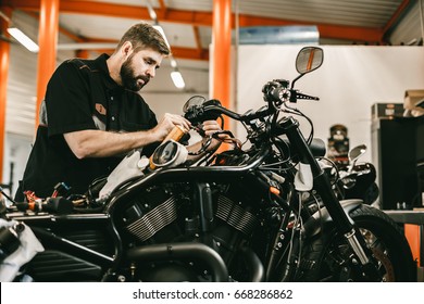 Man Repairing Electronics Sports Black Bike. Confident Young Man Repairing Motorcycle In Repair Shop.