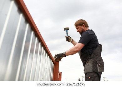 Man Repairing Fence Near House In Summer