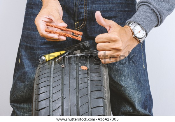 The man repairing flat car tire with
repair kit, Tire plug repair kit for tubeless
tires.