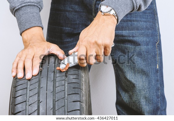The man repairing flat car tire with\
repair kit, Tire plug repair kit for tubeless\
tires.