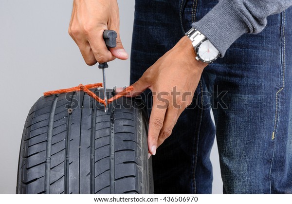 The man repairing flat car tire with\
repair kit, Tire plug repair kit for tubeless\
tires.