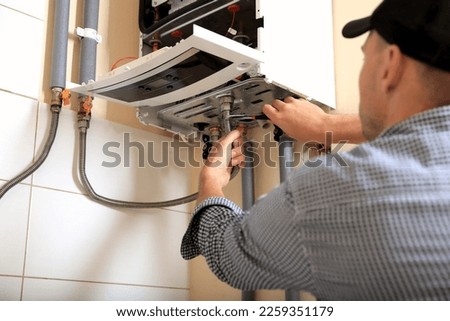 Man repairing gas boiler with waterpump plier indoors, closeup