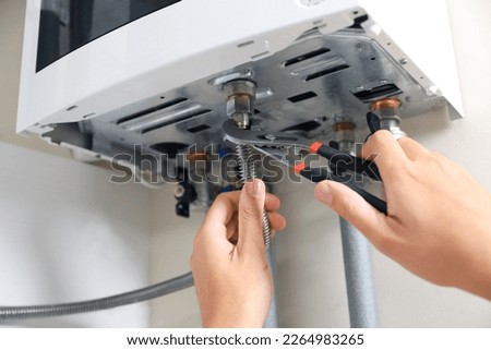 Man repairing gas boiler with waterpump plier, closeup