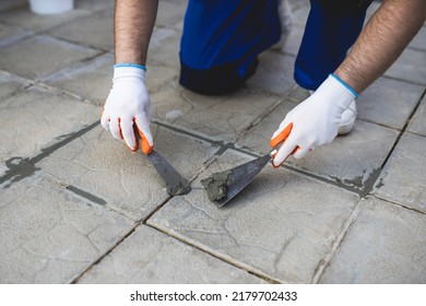 A Man Repairing The Grout On A Tile Floor.