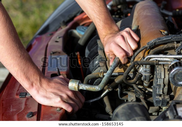 Man repairing motor block\
of a car
