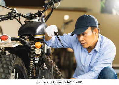 Man repairing motorcycle in repair shop, Mechanic fixing motorbike in workshop garage, Repairing and maintenance concepts - Powered by Shutterstock