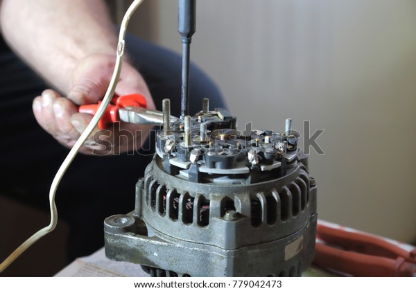 The man is\
repairing an old car generator at\
home.