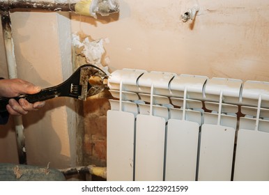 Man is repairing radiator battery in the room. Maintenance repair works renovation in the flat. Heating restoration. Wrench in hands. - Shutterstock ID 1223921599