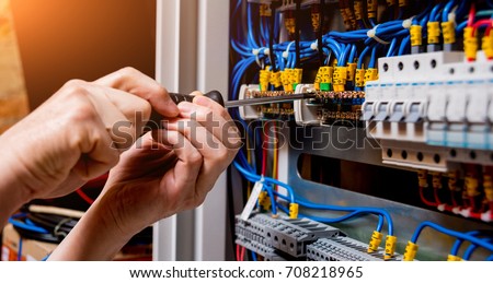 The man is repairing the switchboard voltage with automatic switches. Electrical background