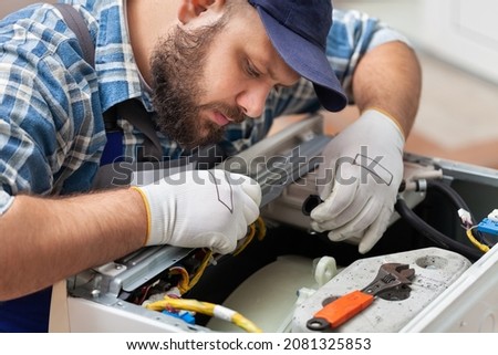 a man repairing a washing machine in cap