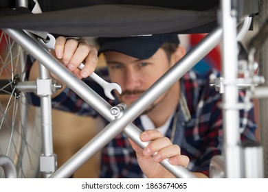 a man is repairing a wheelchair in workshop - Powered by Shutterstock