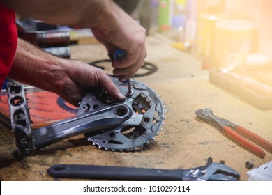 Man Repairs Bike Pedal On Wooden Table