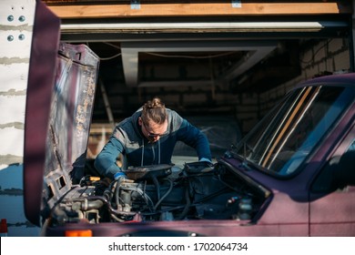 A Man Repairs A Car, Opens The Hood. A Young Guy Looks Under The Hood Of A Car, Self Repair In A Private Garage