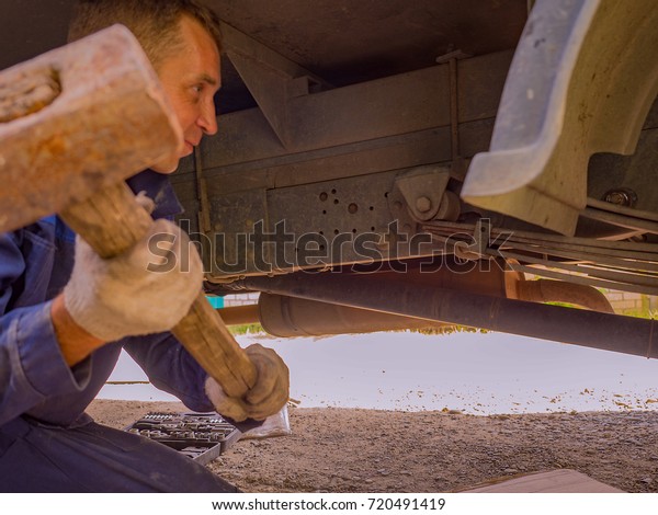 A man repairs a car with a sledgehammer\
technology of maintenance