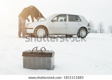 A man repairs a car in winter on snow in the background is a discharged battery, copy space