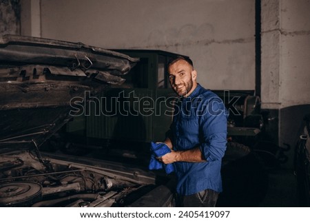 A man repairs an engine in a retro car