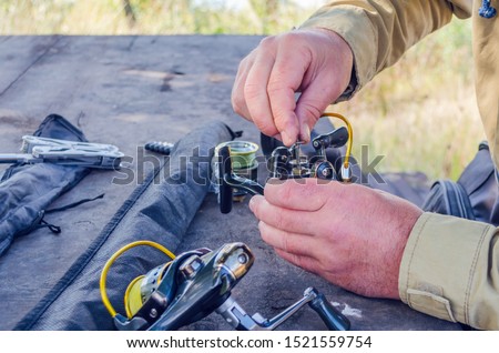 a man repairs a fishing reel with improvised means.