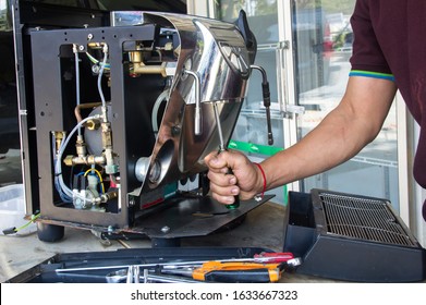 A Man  Repairs The Old Coffee Machine That Is Damaged .