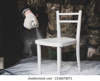 A man repairs old furniture.paints a children's chair with spray paint. handmade concept