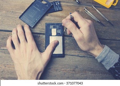 A Man Repairs A Phone.