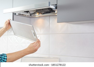 Man repairs range hood in the kitchen. Replacement filter in a cooker hood.