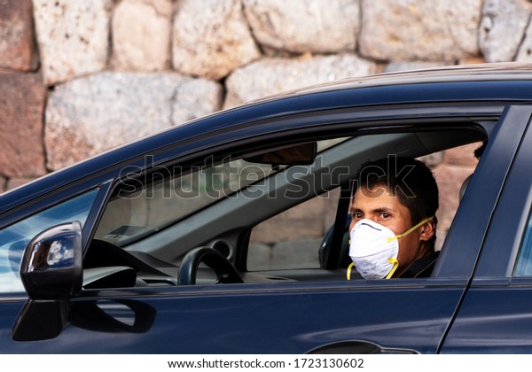 Man\
in repiratory mask in car coronavirus pandemic in Cusco, Peru in\
Latin South America. Epidemic of coronavirus\
covid-19