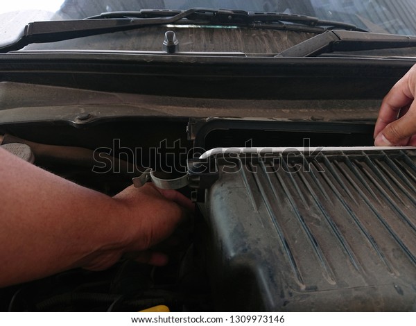 A man \
replacement of new automotive \
 engine air filter in the engine\
air flow with more dust in engine\
room