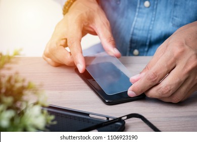 The man replacing the broken tempered glass screen protector for smartphone. - Shutterstock ID 1106923190