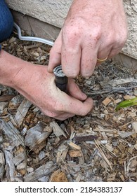 Man Replacing A Sprinkler Head In The Ground With Wood Chips. Sprinkler System Repair.