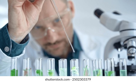 Man researcher with safety glasses is working with lab tubes using a pipette in laboratory, close-up of lab equipment. Science and medicine - Powered by Shutterstock