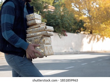 Man In A Residential Neighborhood Holds A Pile Of Christmas Presents In A Winter Day After Shopping. Christmas Shoping Day 2020. 