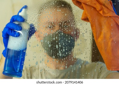 Man In Respirator Mask And Gloves Disinfects Window Surface With Spray Solution