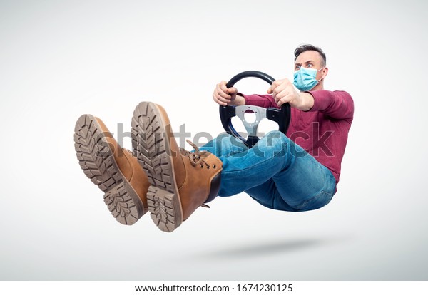 Man in respiratory mask drives a\
car while holding a steering wheel. Attention virus\
concept
