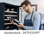 Man, restaurant and waiter in wine cellar with smile for service, hospitality and professional. Employee, alcohol and happy or satisfied in winery with stock check for customer and luxury beverage