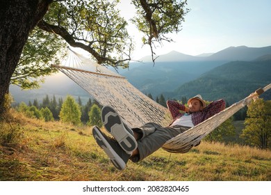 Man resting in hammock outdoors at sunset - Shutterstock ID 2082820465