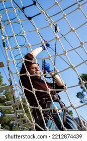 A Man Is Resting In A Rope Amusement Park. Vertical Photo.