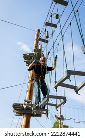 A Man Is Resting In A Rope Amusement Park. Vertical Photo.