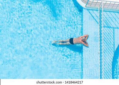 A Man Is Resting And Sunbathing In The Pool, View From Above