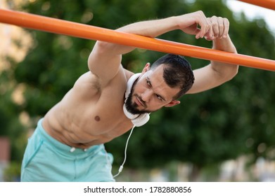 A man rests after doing push UPS on the bars outside