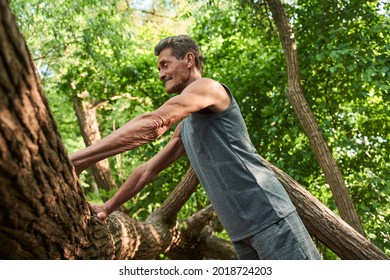 Man rests on a tree trunk and preparing doing push ups around the nature